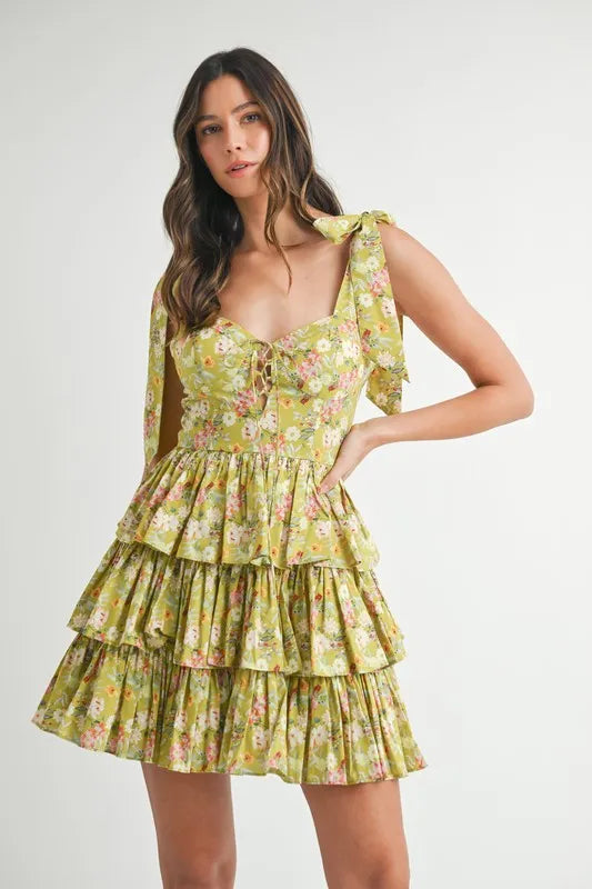 Woman wearing lime green floral tiered mini dress with tie shoulder straps and lace-up bodice front view
