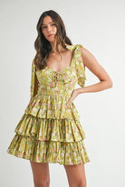 Woman wearing lime green floral tiered mini dress with tie shoulder straps and lace-up bodice front view
