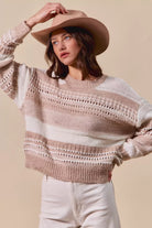 Woman wearing a striped sweater and beige hat against a beige background