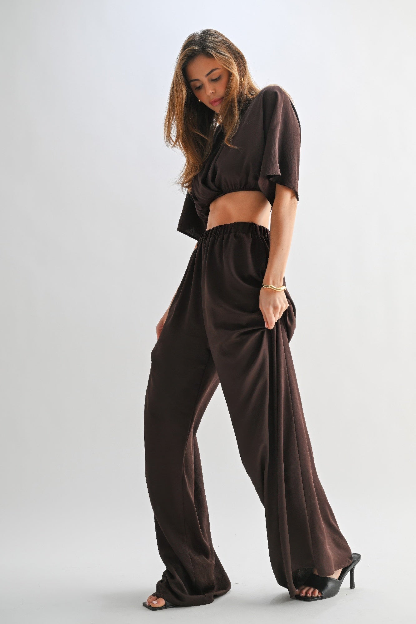 Model showcasing wide leg relaxed fit of chocolate brown lounge set. 