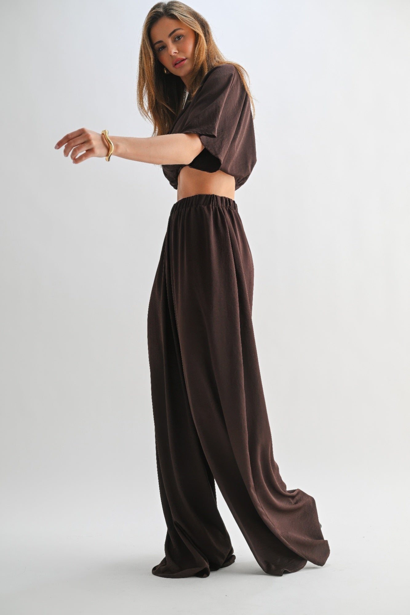 Side view of model walking in chocolate brown crop top and pant lounge set.