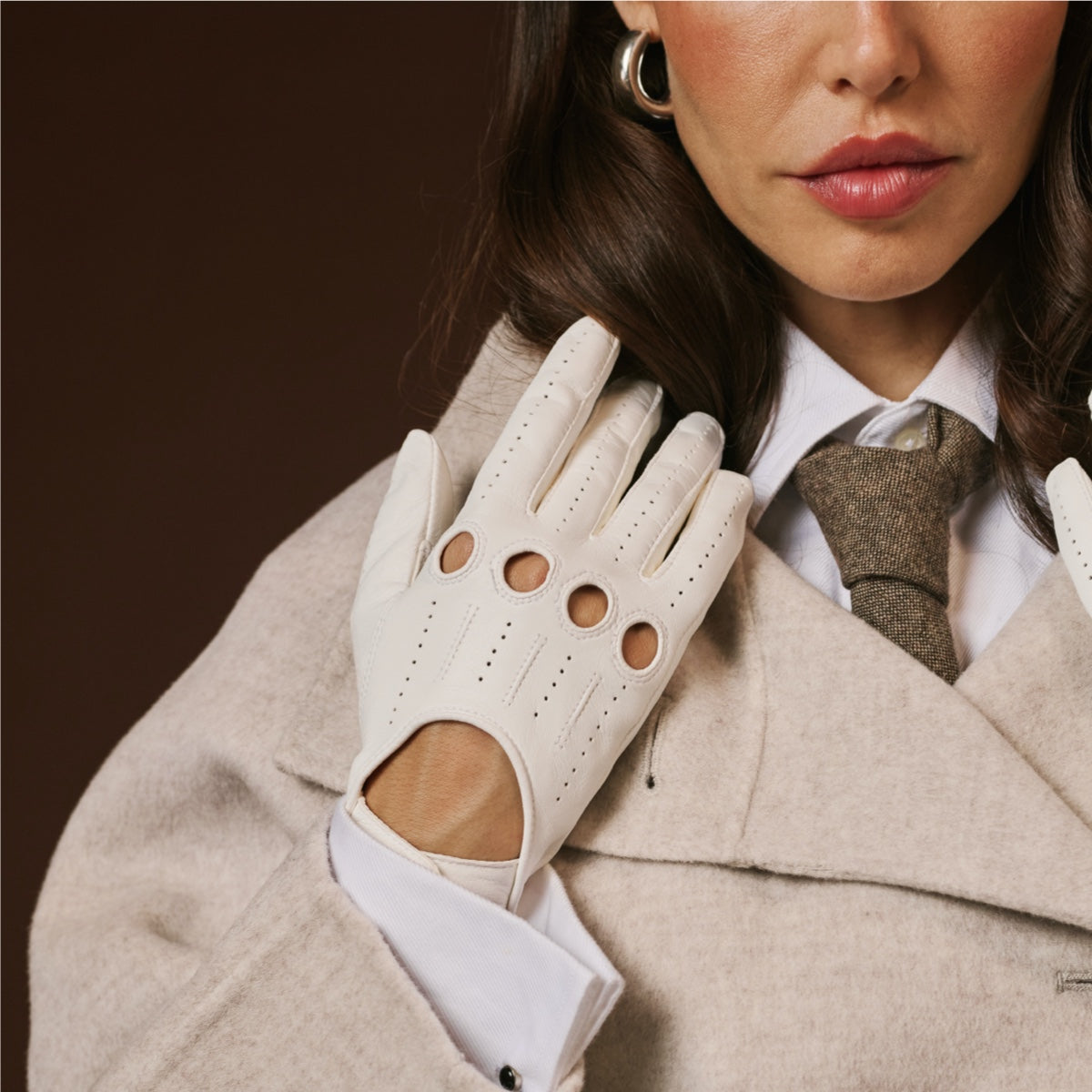 Woman wearing a white leather glove with cut-out design, dark background