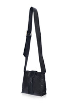 A black leather shoulder bag with a long strap, featuring a front flap with a tassel and decorative stitching, shown against a plain white background.