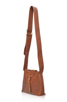 Camel leather handbag with fringe details and wide crossbody strap on a white background, 3/4 view