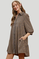 Brown and grey plaid shirt dress with collared neckline, chest pocket, contrast piping and side patch pocket.

