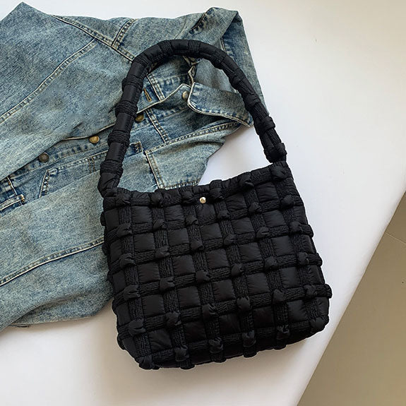 Black woven tote on a white surface with a denim jacket