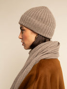Person wearing a beige knit hat and scarf against a plain background