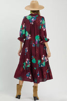 Back view of burgundy floral midi dress showing relaxed tiered silhouette and colorful floral print.
