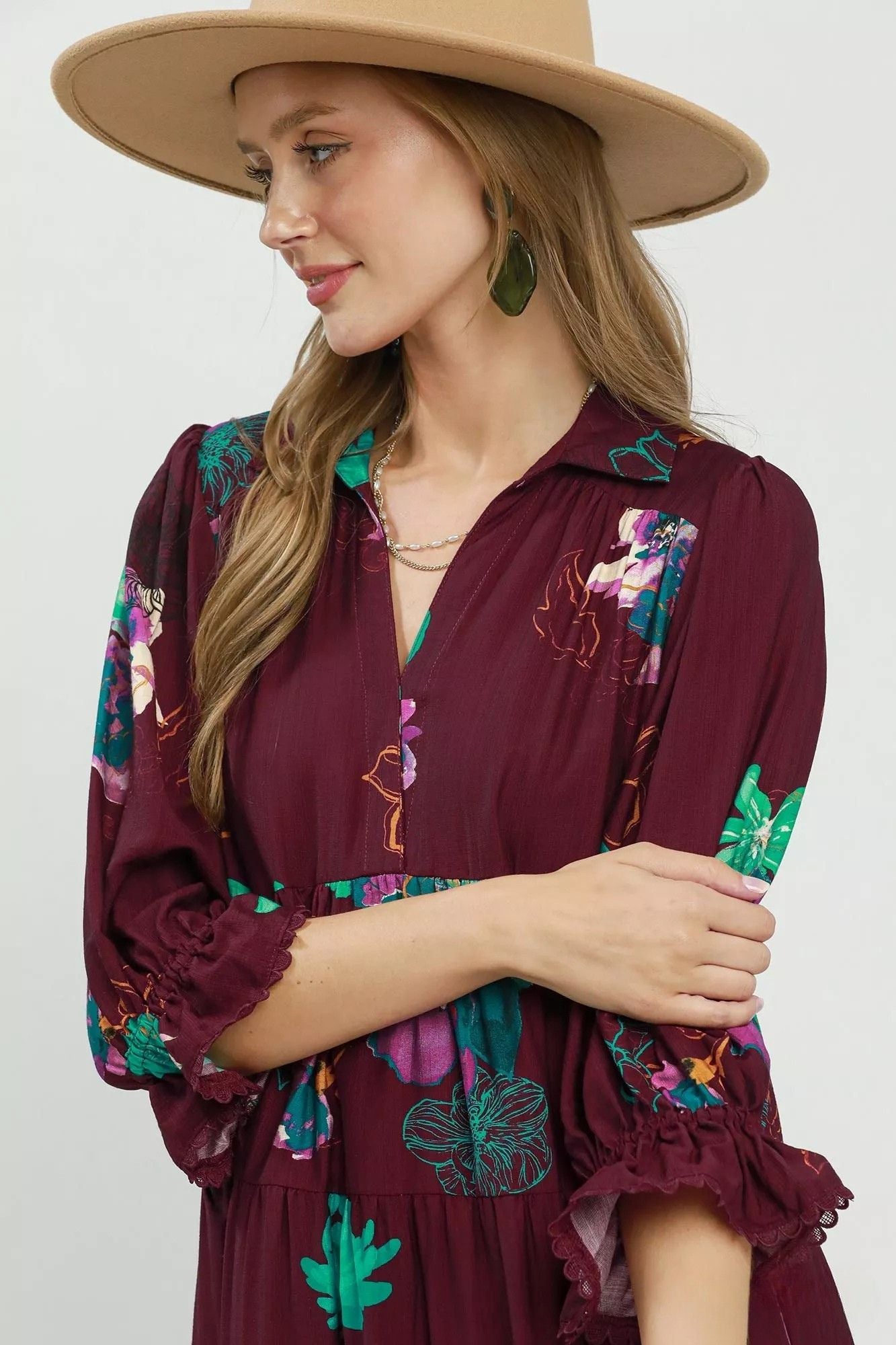 Close view of burgundy floral midi dress showing V neckline, gathered bodice and ruffled sleeve detail.
