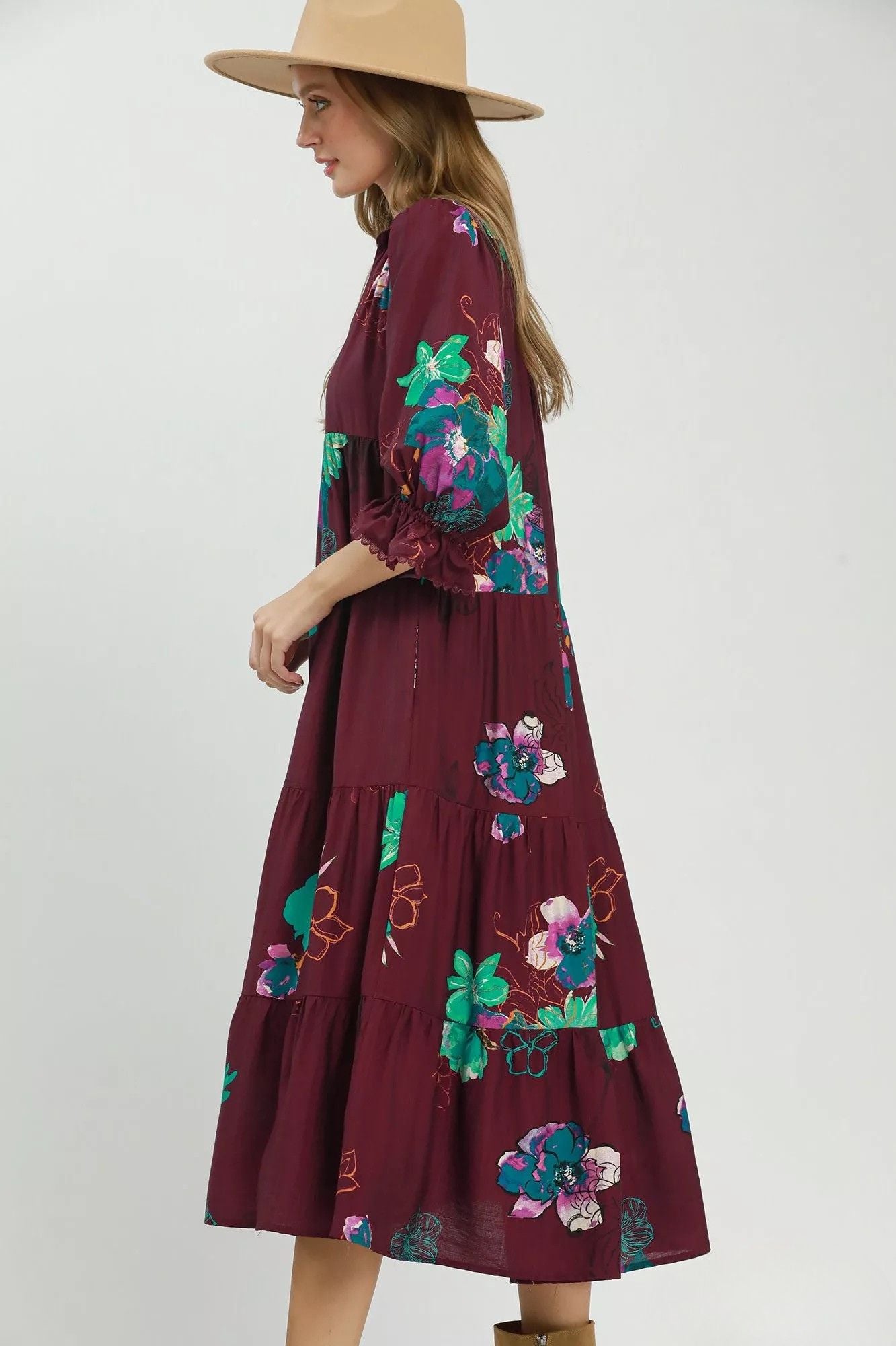 Side view of burgundy floral tiered midi dress with three quarter sleeves and ruffled cuffs.