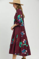 Side view of burgundy floral tiered midi dress with three quarter sleeves and ruffled cuffs.
