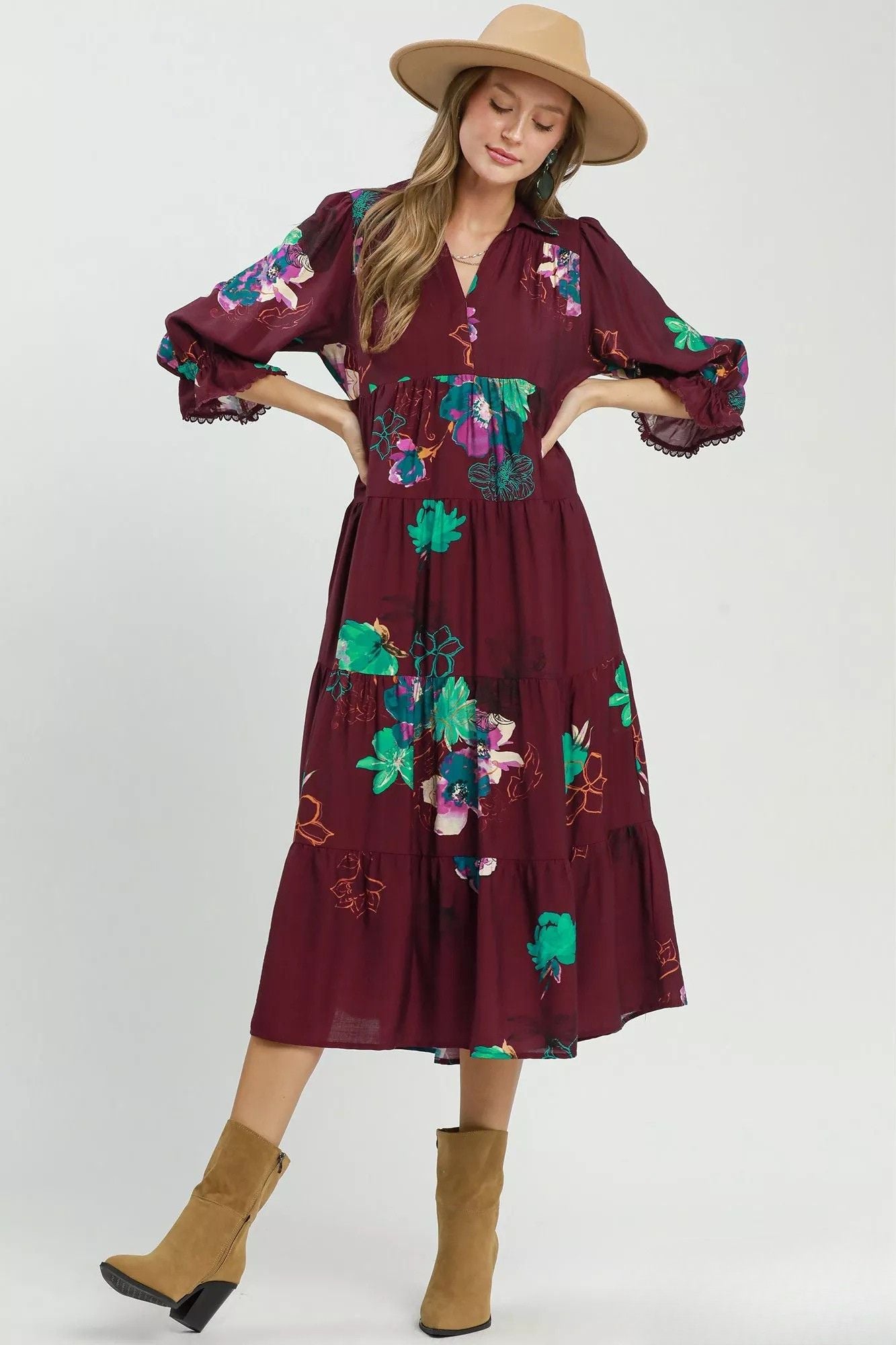 Burgundy floral midi dress with flowing tiered skirt styled with tan boots and wide brim hat.
