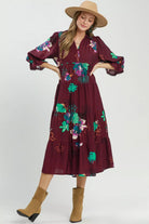 Burgundy floral midi dress with flowing tiered skirt styled with tan boots and wide brim hat.
