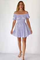 Woman wearing a light purple off-shoulder cotton mini dress on a white background, front view