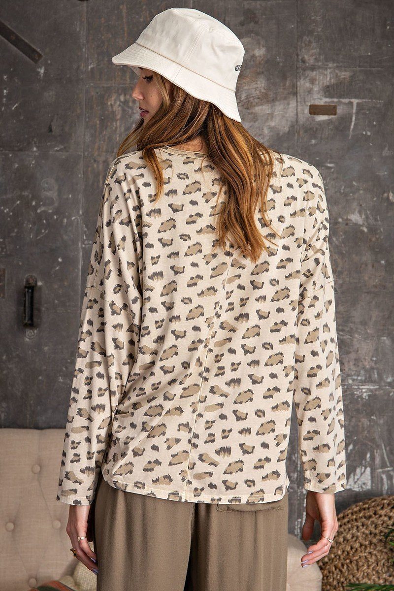 Back view of a beige leopard print oversized knit top with dolman sleeves and relaxed fit, styled with khaki jogger pants and bucket hat.
