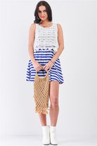 Model holding woven tote wearing blue striped sleeveless mini dress with crochet lace top
