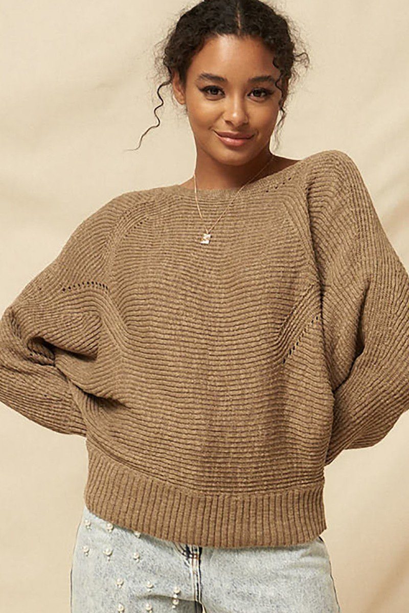 Woman wearing a cozy taupe rib knit sweater with boatneck neckline, relaxed fit, and eyelet details, paired with light wash pearl-embellished jeans-AVAH
