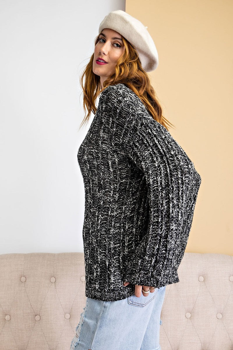 Side view of marled black and white rib knit sweater showing relaxed sleeves and texture.
