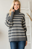 Grey and cream striped ribbed turtleneck sweater worn by a blonde model facing forward.