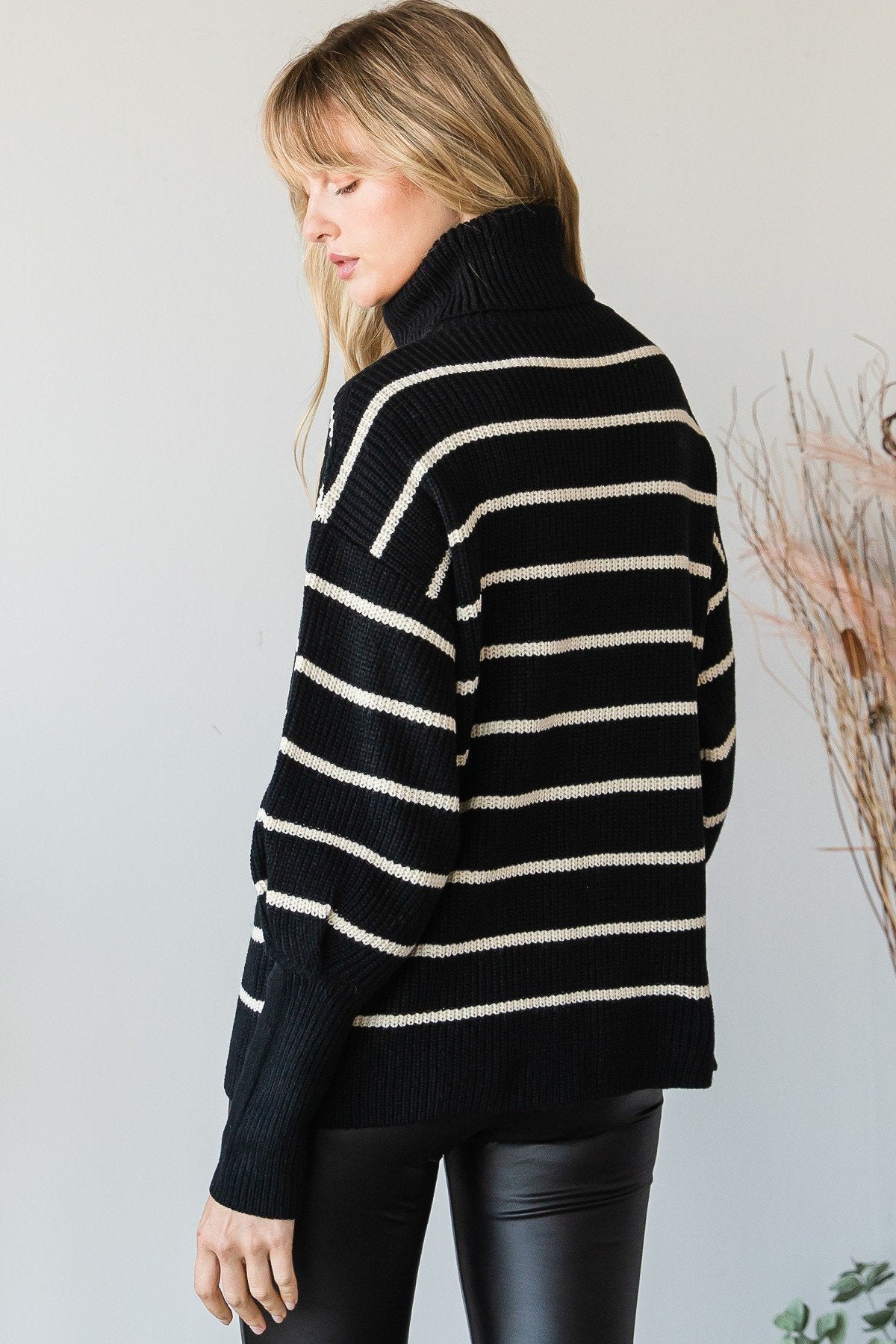 Back view of black and ivory striped turtleneck sweater showing relaxed fit, dropped shoulders, and ribbed hem.