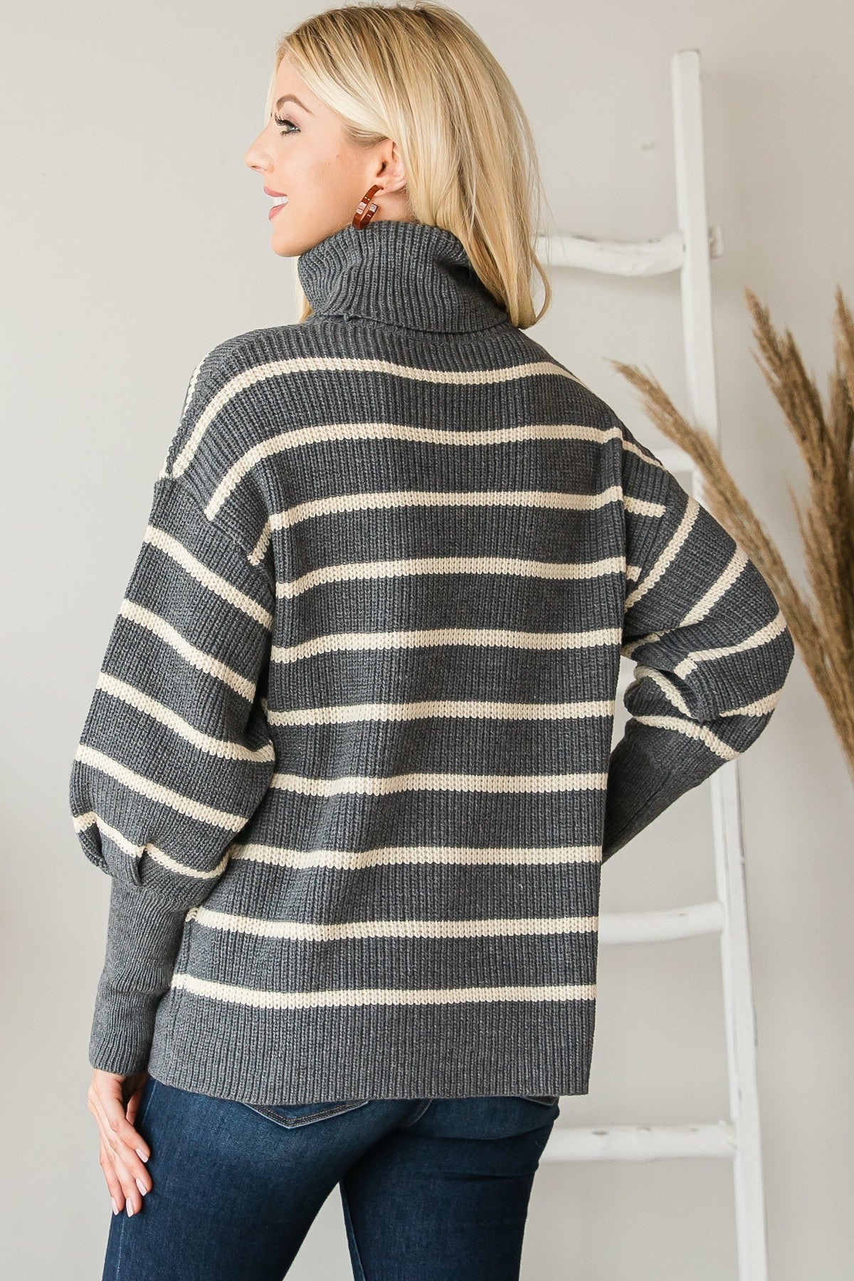 Back view of grey and cream striped turtleneck sweater, showing drop shoulders and ribbed knit texture.