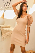 Model posing in taupe ribbed dress with sheer sculpted rosette sleeves, front angled view.