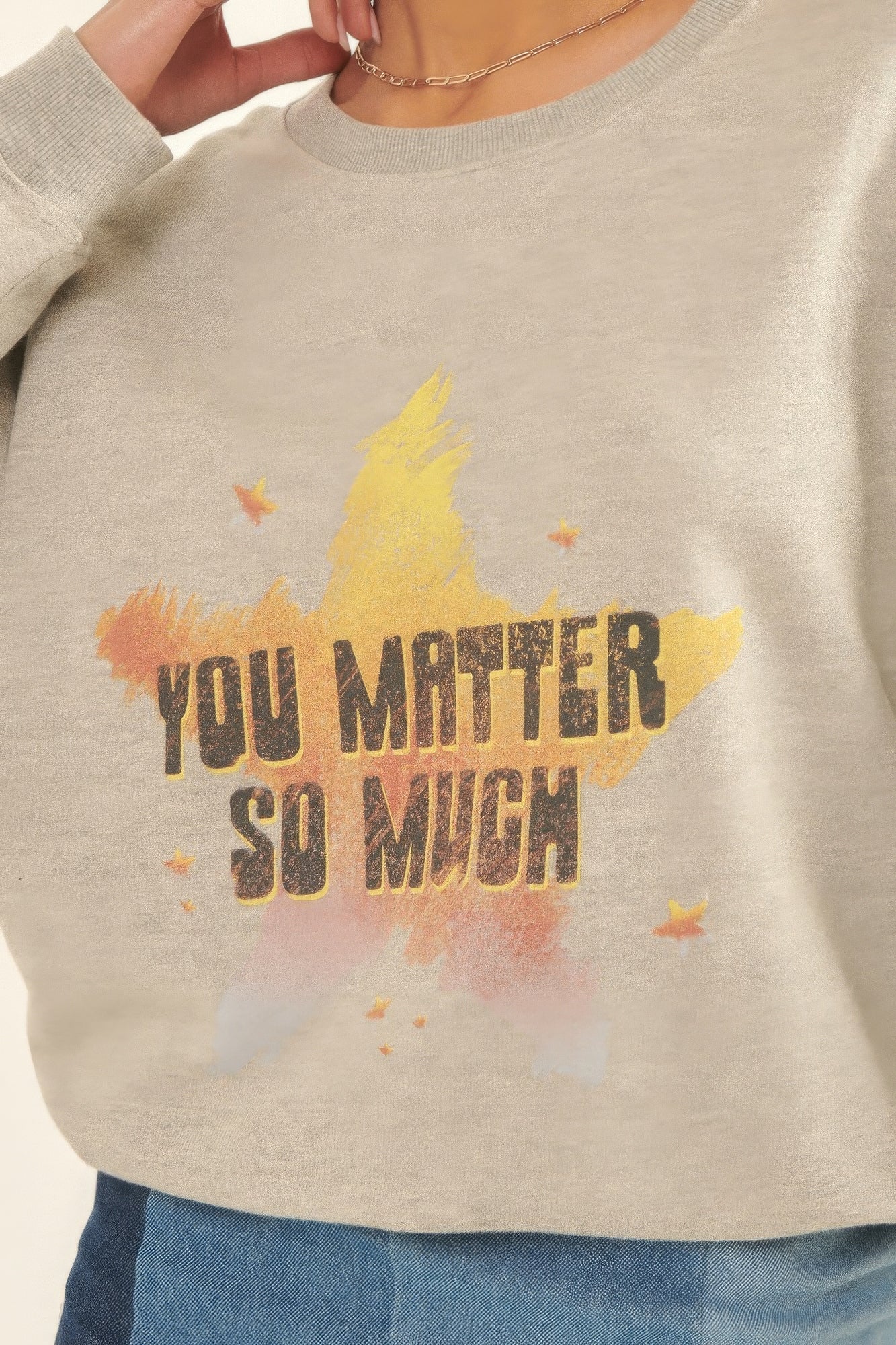 Close-up of Radiance Reminder Graphic Sweatshirt with yellow and orange star design and bold lettering