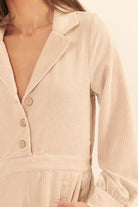 Close-up of cream romper showing ribbed corduroy texture and button detail at the front