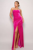 Fuchsia strapless maxi dress featuring a sculpted bodice, wrapped front hem, and thigh high slit.
