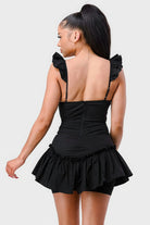 Back view of black mini dress with fitted waist and layered ruffle hem