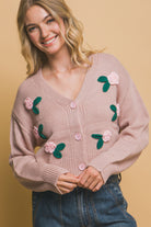 Model wearing a pink sweater with floral embellishments