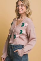 Side view of dusty pink cropped cardigan with floral detailing and long sleeves.
