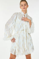 Front angled view of white metallic mini dress with feather cuffs and belted waist.