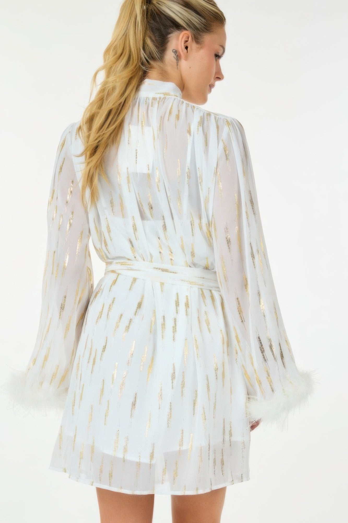 Back view of white and gold metallic mini dress with feather-trim sleeves and belted waist.