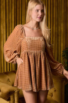 Angled view of model wearing velvet romper with relaxed flared shorts and long sleeves