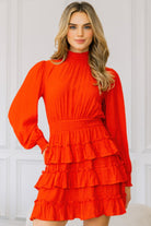 Model wearing a bold red long sleeve mini dress with smocked neckline and tiered ruffle skirt, front view-AVAH