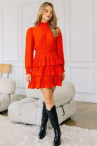 Full-length view of model in red smocked high-neck ruffle mini dress styled with black boots-AVAH