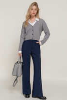 Model in navy straight-leg pants paired with a grey cardigan and white shirt
