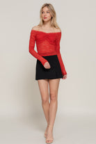 Red sheer lace off-shoulder top styled with black mini skirt.”