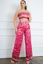 Model wearing a pink satin two piece set featuring a cropped camisole top and wide leg printed pants.
