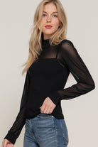 Side view of black ribbed knit sweater top showing draped silhouette and soft lightweight texture.