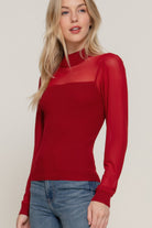 Side view of red ribbed knit sweater top showing draped silhouette and soft lightweight texture.