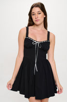 Front view of black mini dress with contrast white bow and trim, featuring sweetheart neckline and gathered skirt.