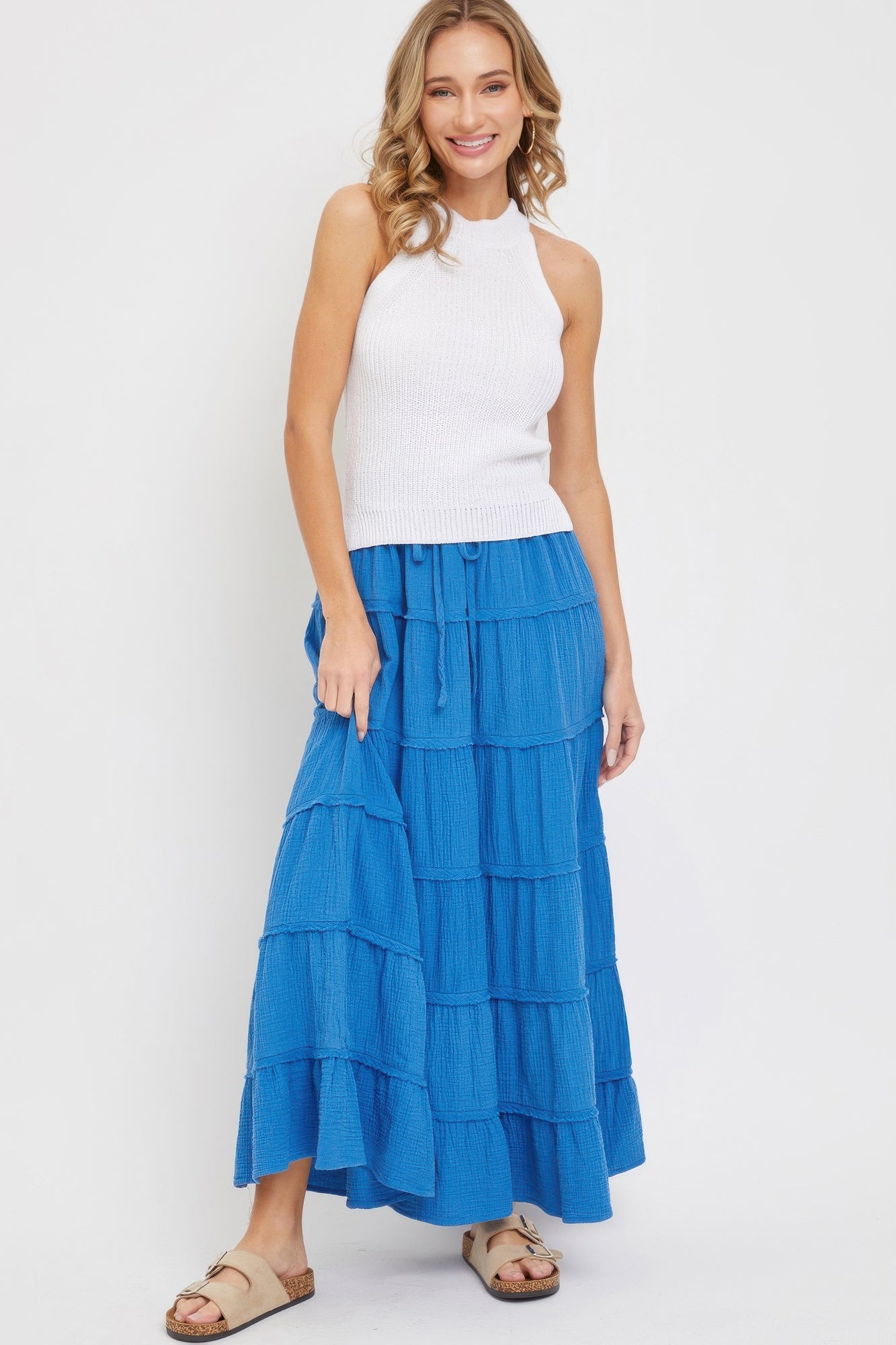Woman wearing bright blue tiered cotton maxi skirt with white knit halter top
