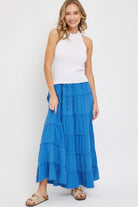 Woman wearing bright blue tiered cotton maxi skirt with white knit halter top
