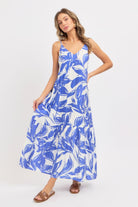 Model wearing a blue and white floral maxi dress on a white background
