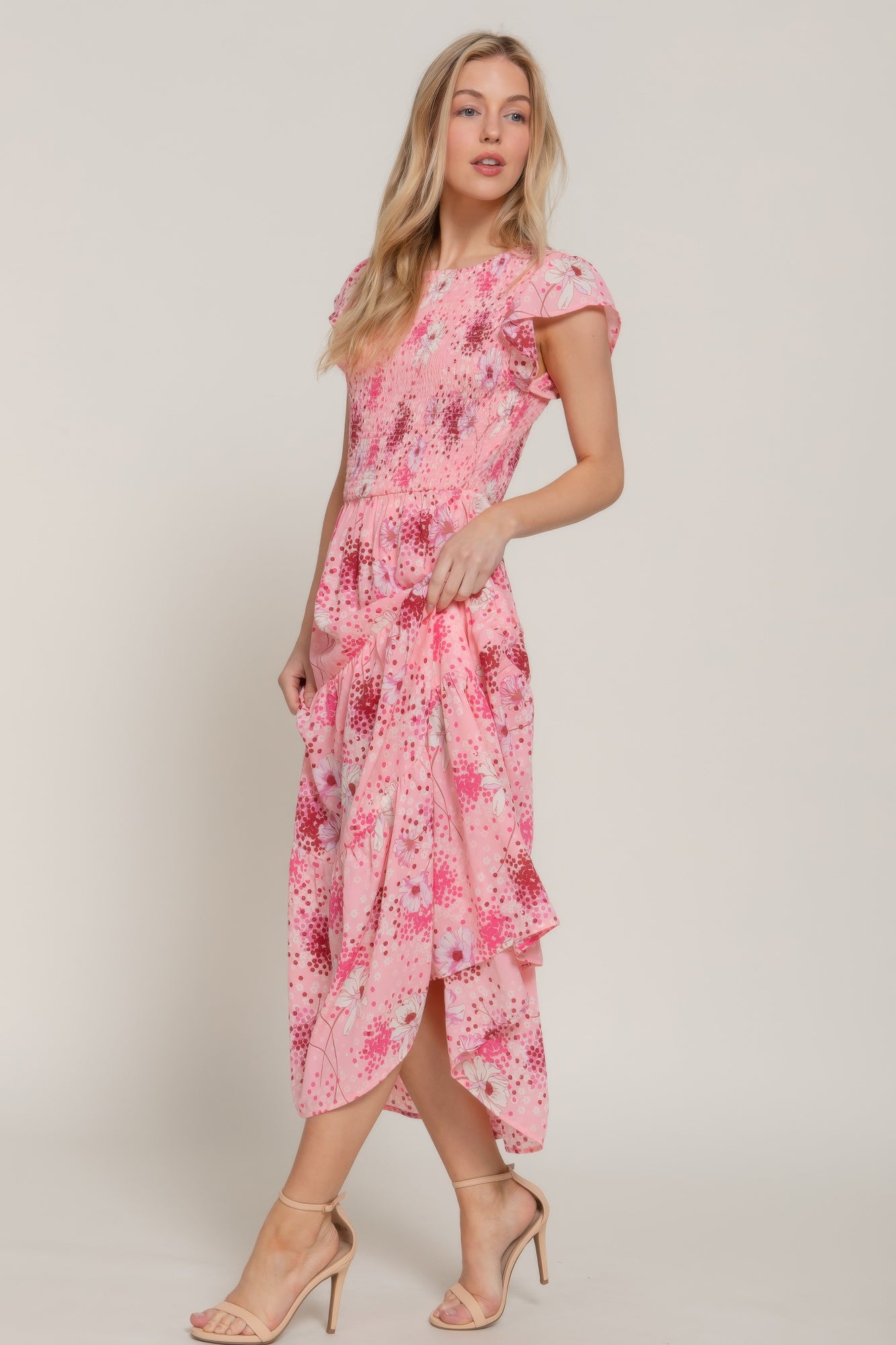 Side view of pink floral smocked maxi dress with flutter sleeves.
