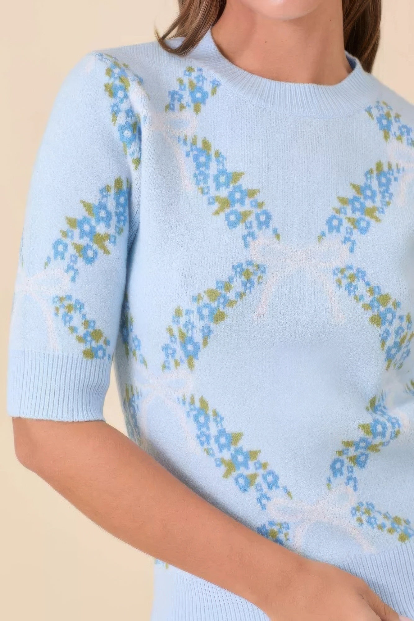 Close-up of floral lattice knit pattern on light blue sweater.
 image