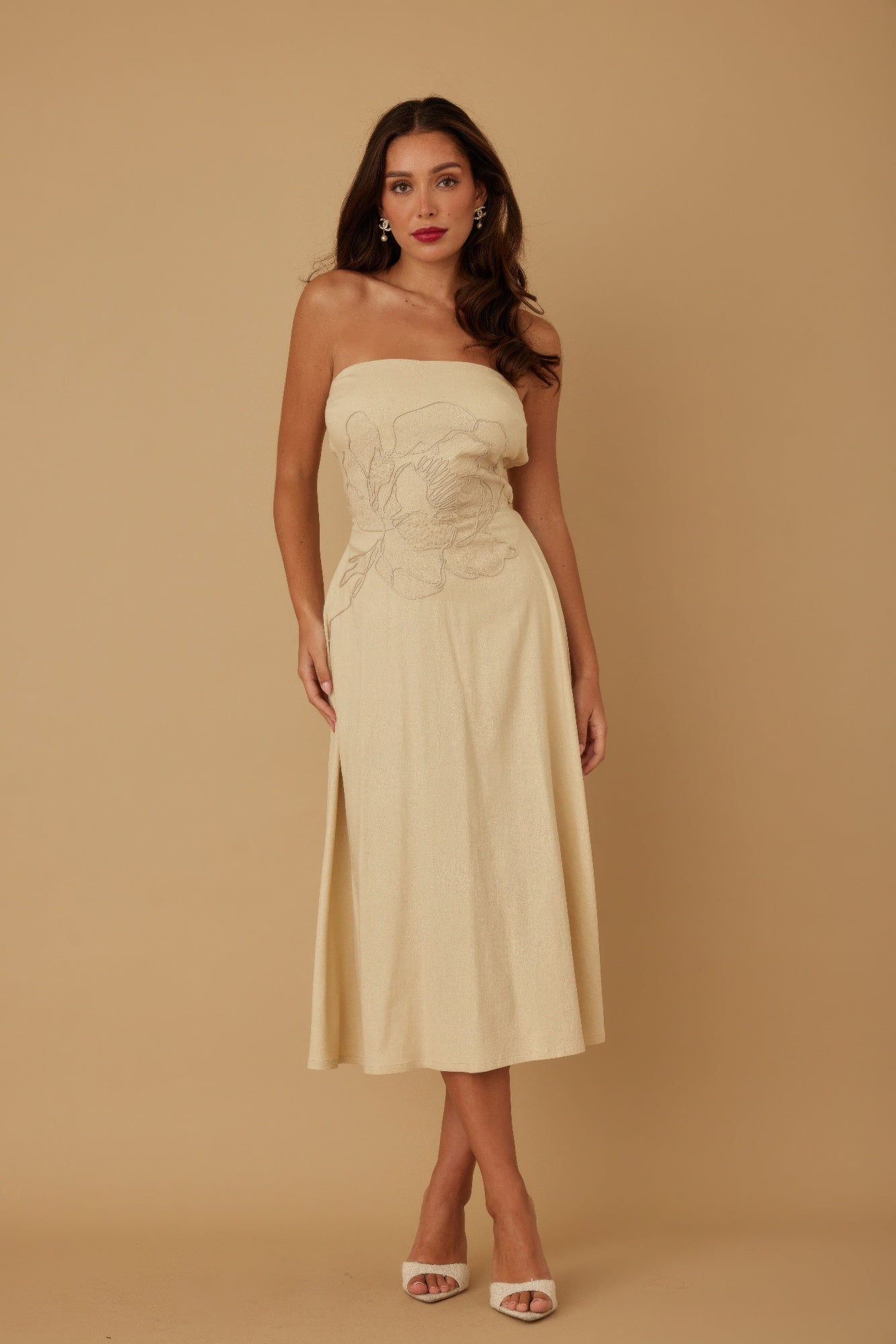 Model standing front-facing in beige strapless midi dress with floral embroidery at bodice
