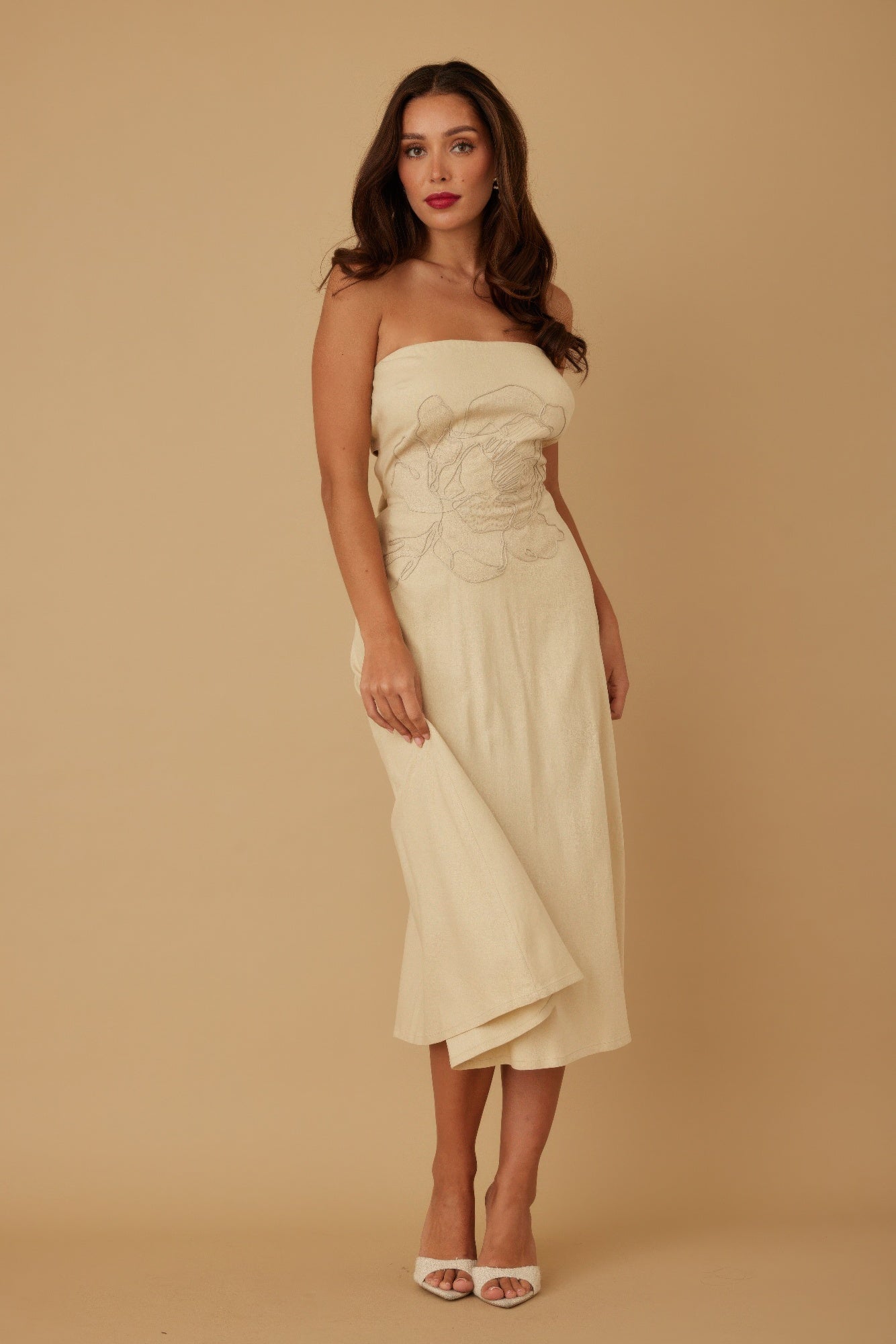 Model standing front-facing in beige strapless midi dress with floral embroidery at bodice
